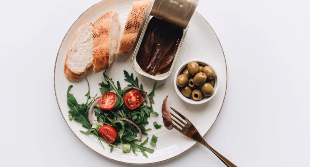 Mediterranean diet plate of bread, fish, green salad and olives